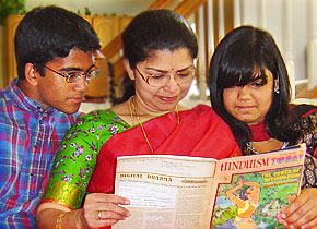 Mrs. Kalugotla reading Hinduism Today to her children